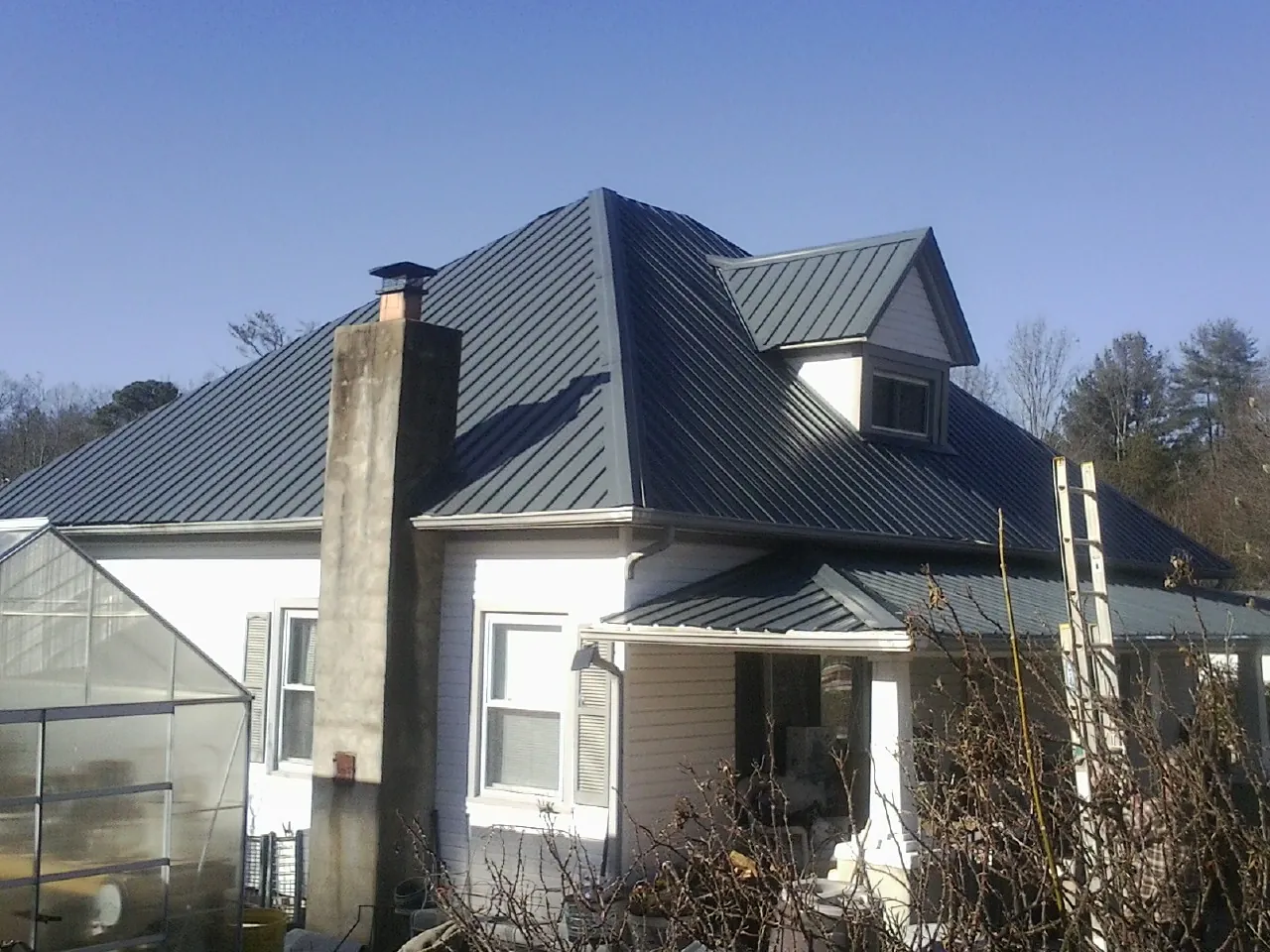 Dark blue standing seam metal roof on a white farmhouse with dormer — Slate & Tile Roof Repair by Roofing Brothers in Rocky Hill